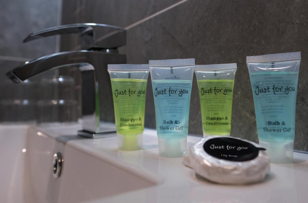 Un bagno con un lavandino, quattro articoli da toilette con l'etichetta 'Just for you' e una saponetta.