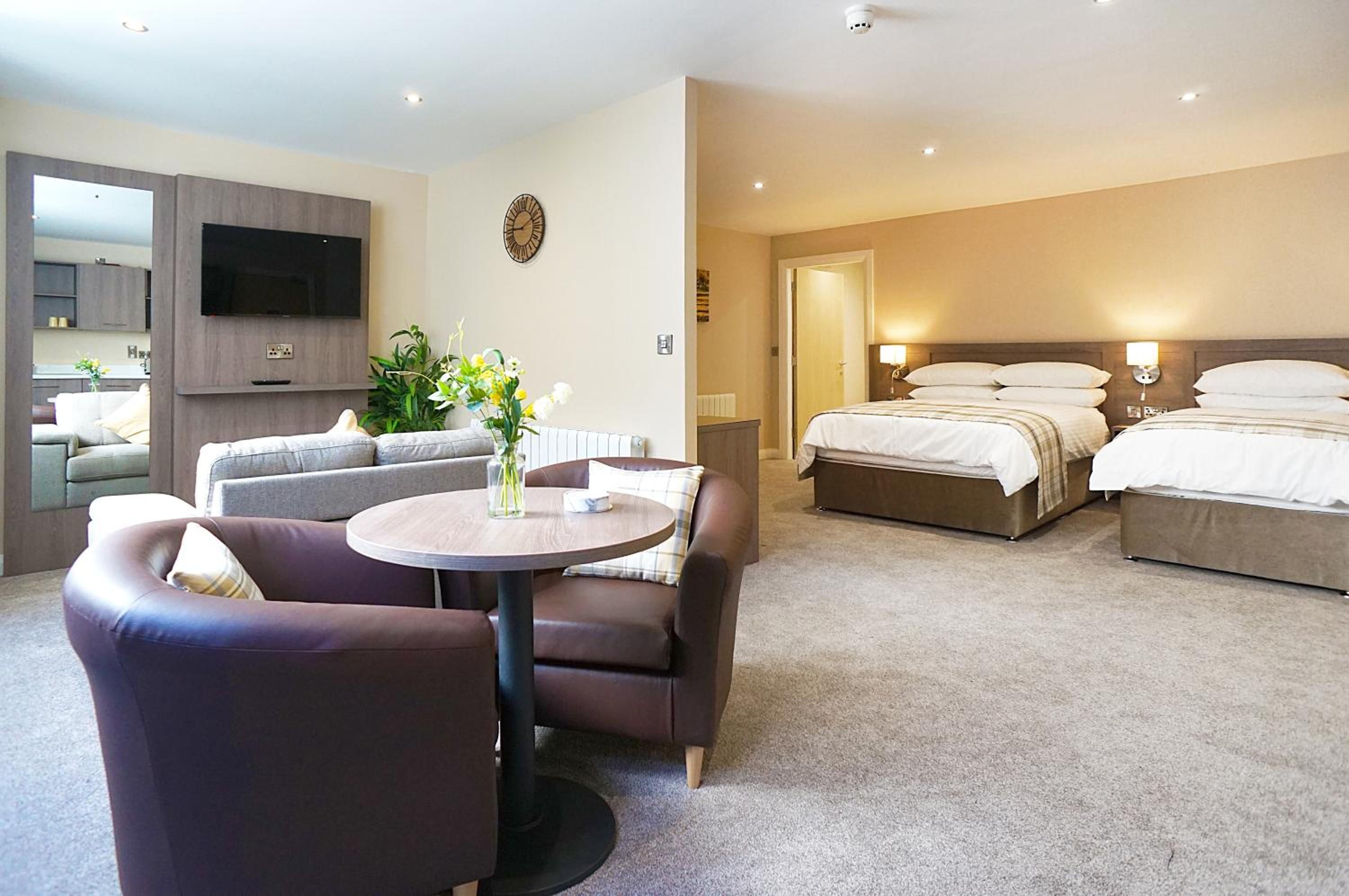 Une chambre d’hôtel équipée d’un canapé, d’une table ronde, d’un lit et d’un téléviseur fixé au mur.