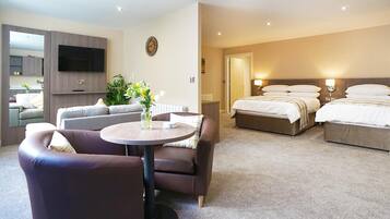 Une chambre d’hôtel équipée d’un canapé, d’une table ronde, d’un lit et d’un téléviseur fixé au mur.