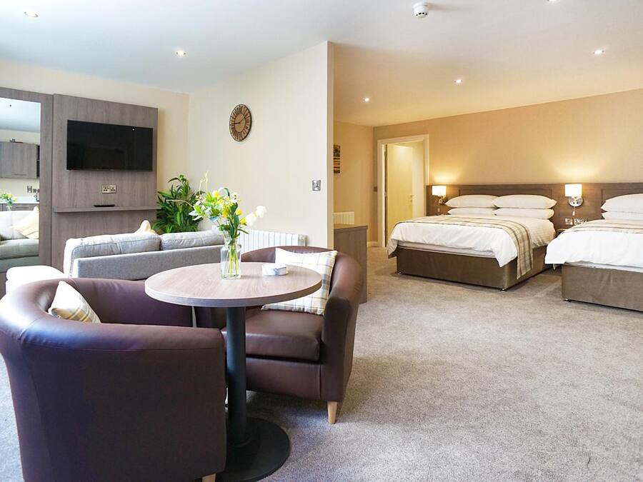Une chambre d’hôtel équipée d’un canapé, d’une table ronde, d’un lit et d’un téléviseur fixé au mur.