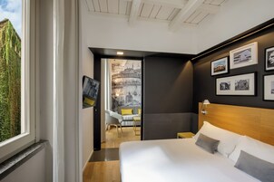 A modern hotel room with a large bed, a wooden headboard, and a cityscape view through a window.