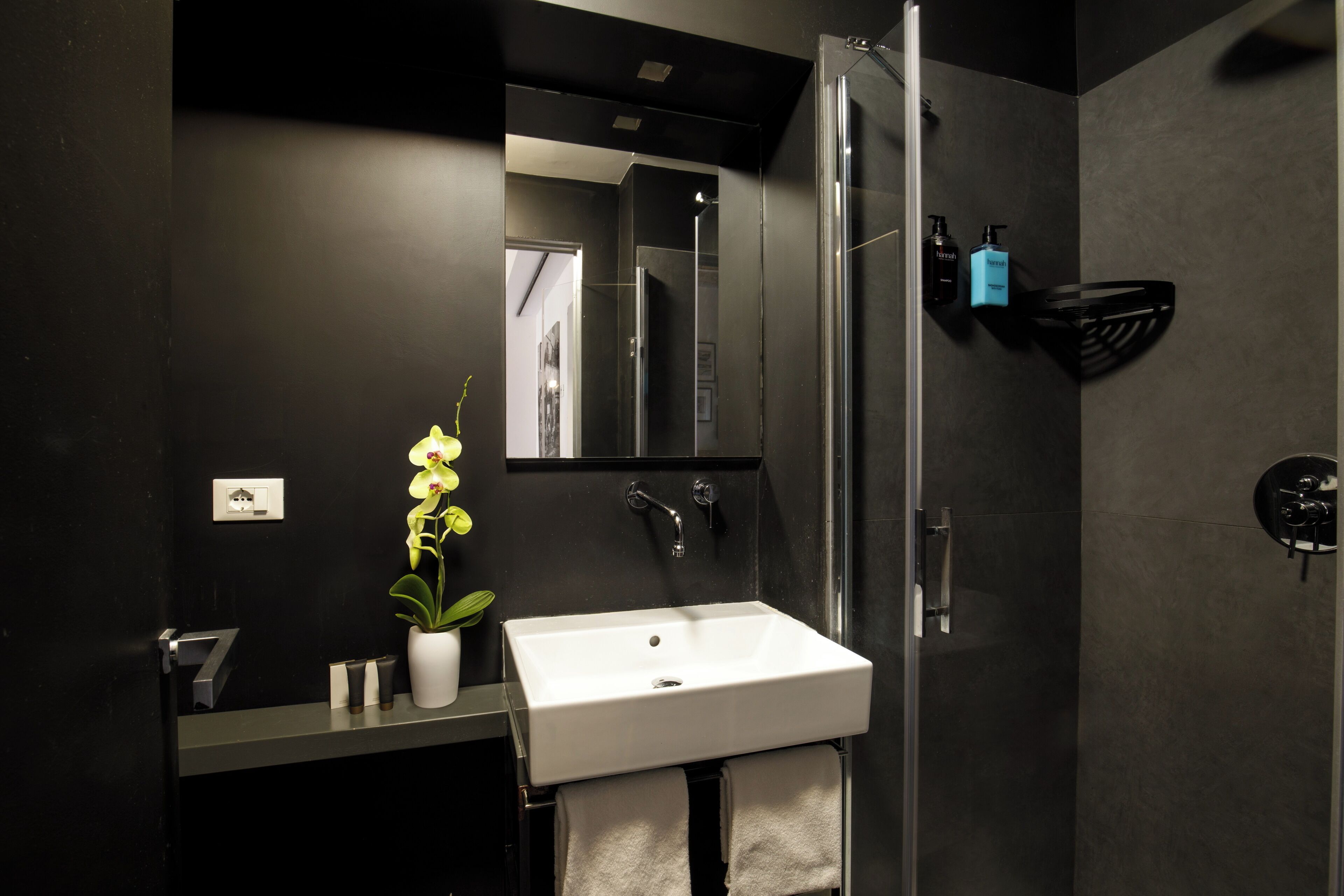 Un baño moderno con un lavamanos blanco, un espejo, una ducha y un perchero para toallas.