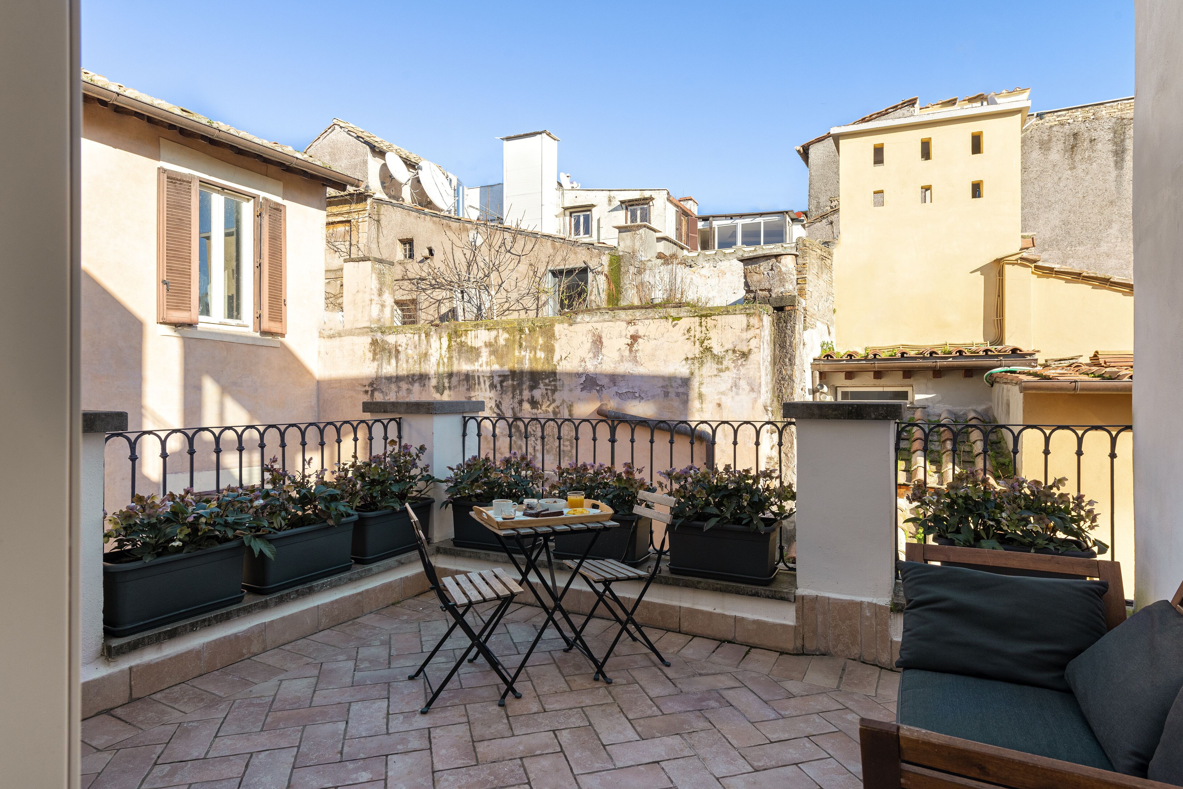 A patio with a table and chairs, surrounded by potted plants and a railing.