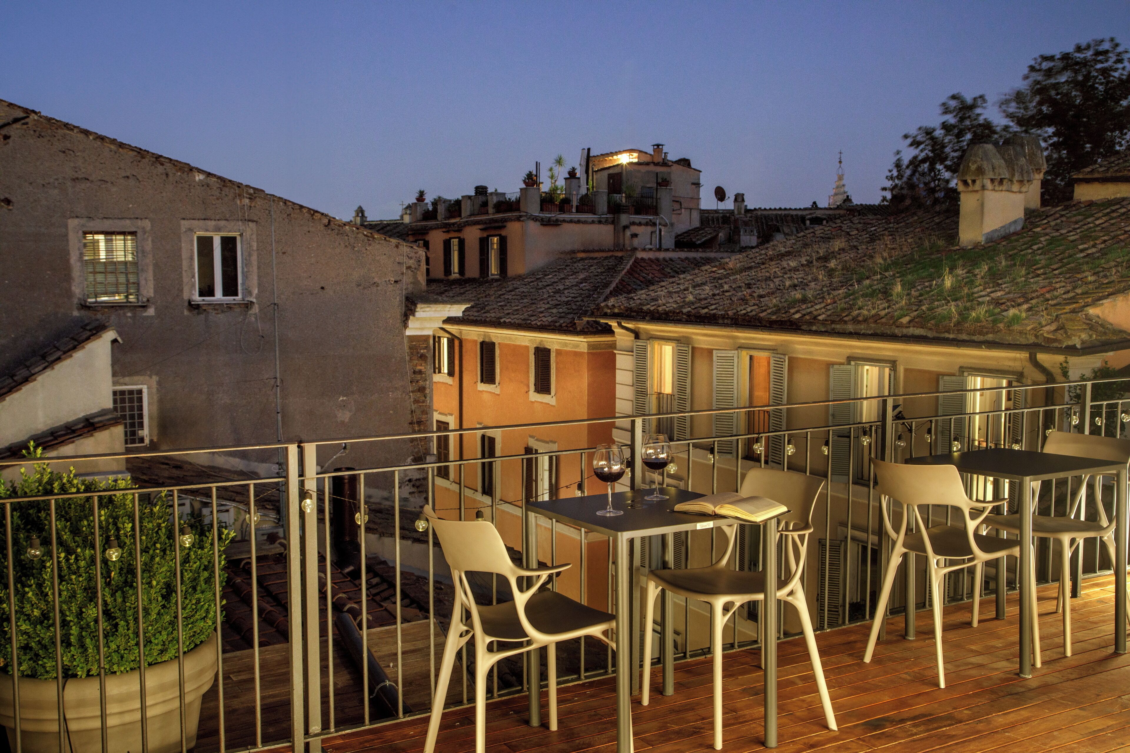 A terrace with a table and chairs, overlooking a cityscape with buildings and a church spire.