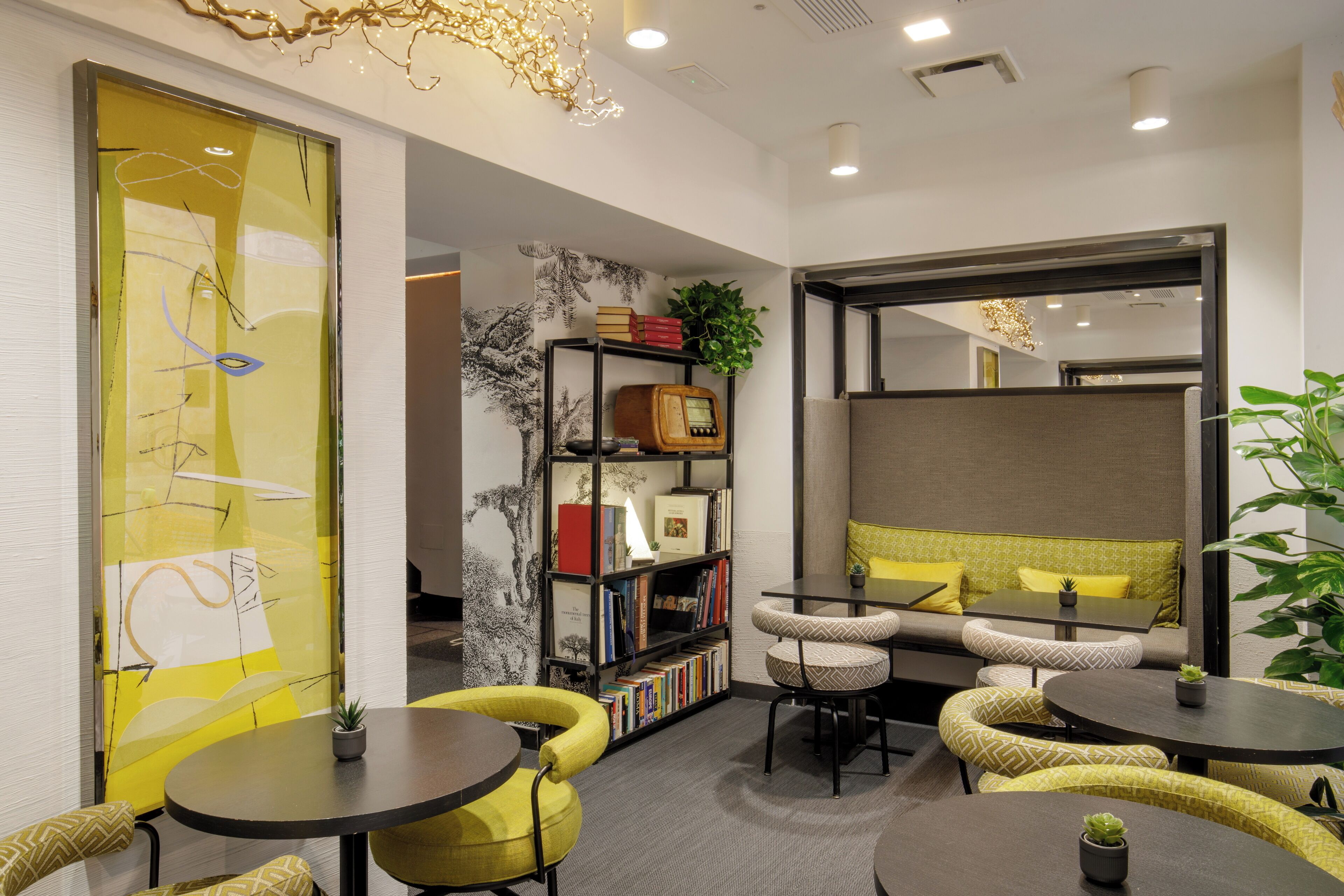 A modern lounge area with seating, a bookshelf, and a decorative wall.