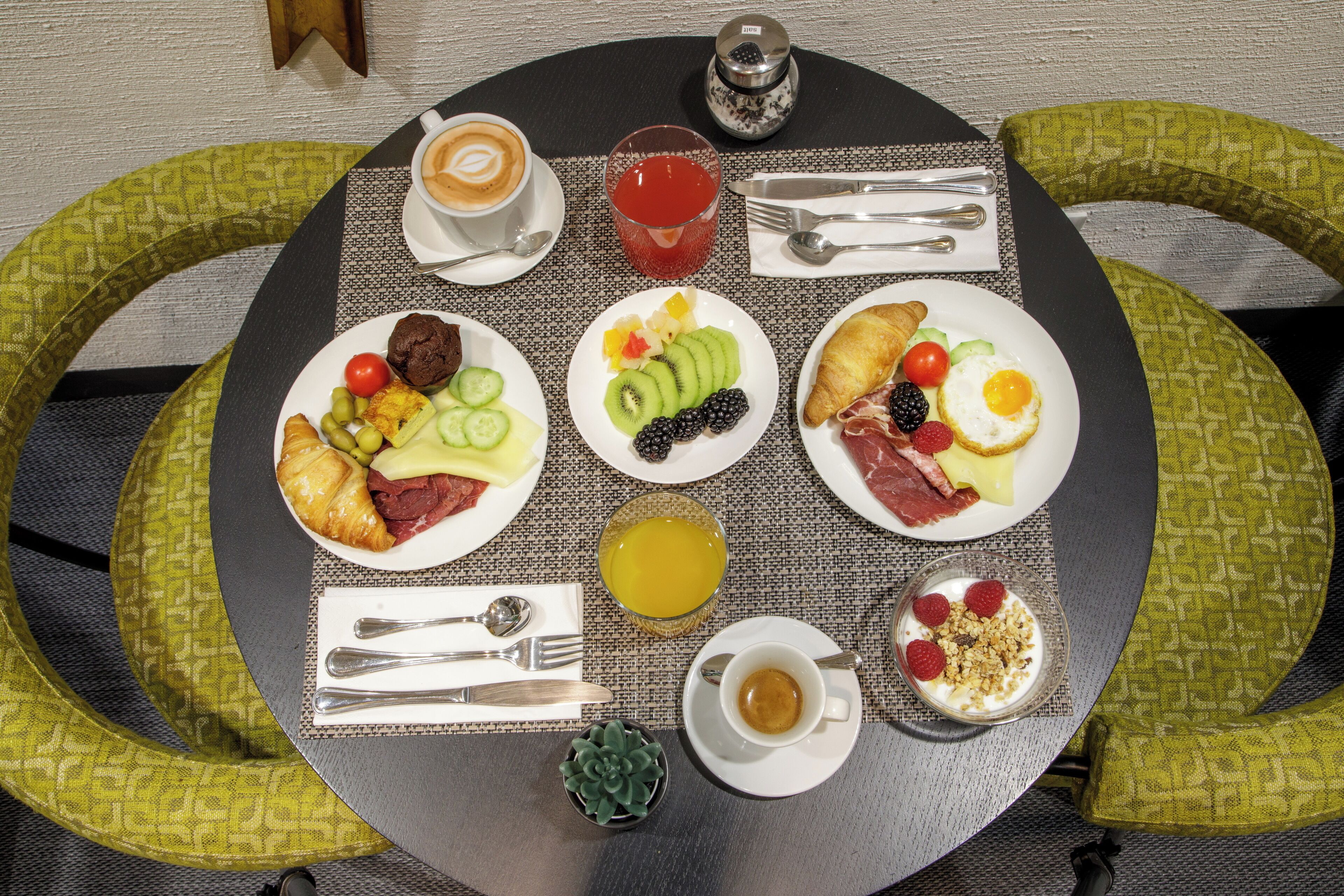 A breakfast table with plates of food, drinks, and cutlery.