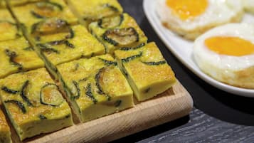 A close-up of a dish with sliced vegetables and eggs on a wooden board.