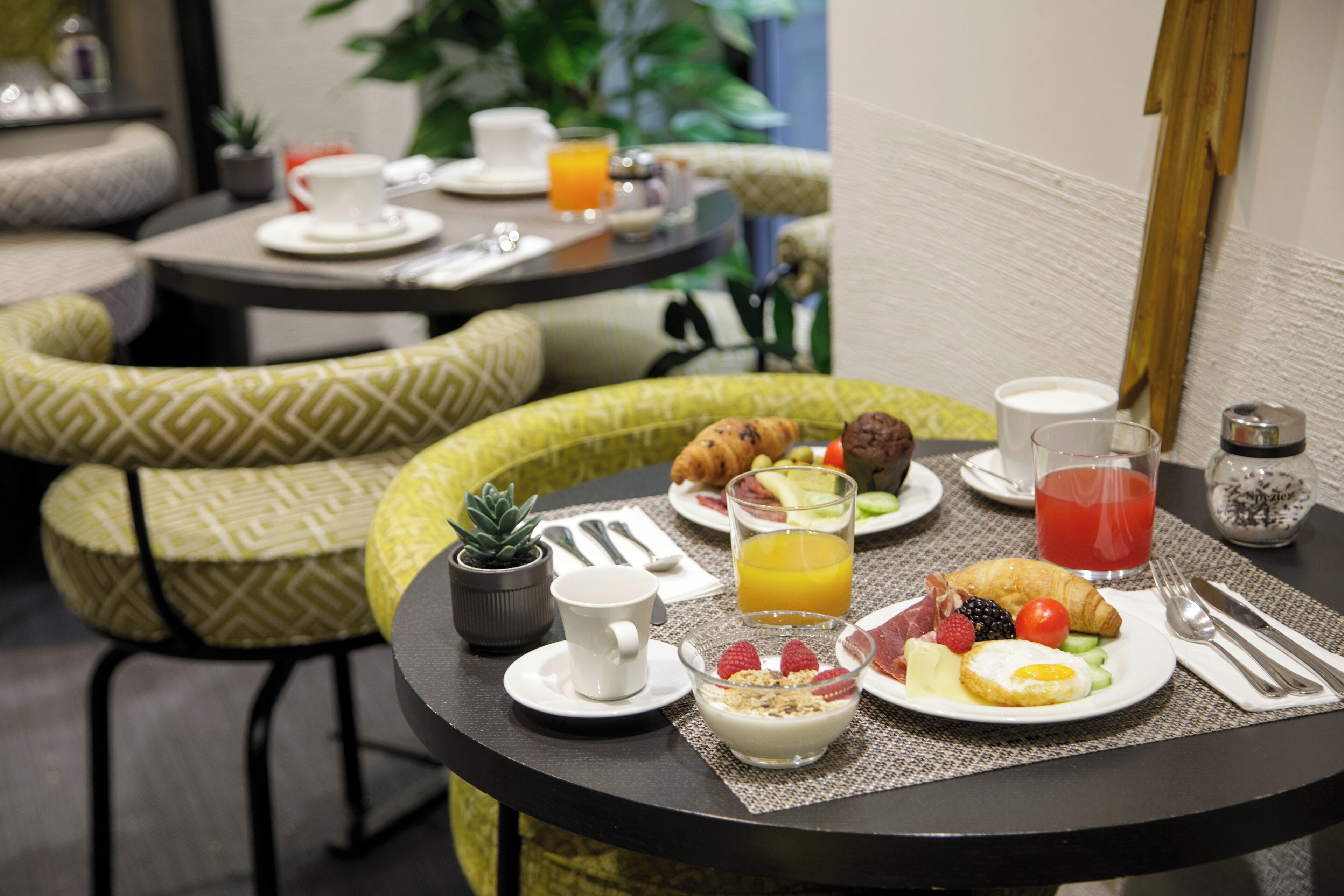 A breakfast setup with plates of food, a cup of coffee, and a glass of orange juice on a table.