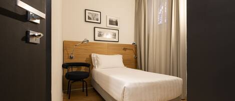 A hotel room with a bed, a chair, a desk, and a nightstand.
