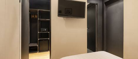A bedroom with a bed, a TV mounted on the wall, and a closet with shelves.