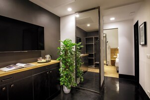 A modern bathroom with a dark-toned vanity, a large mirror, and potted plants.
