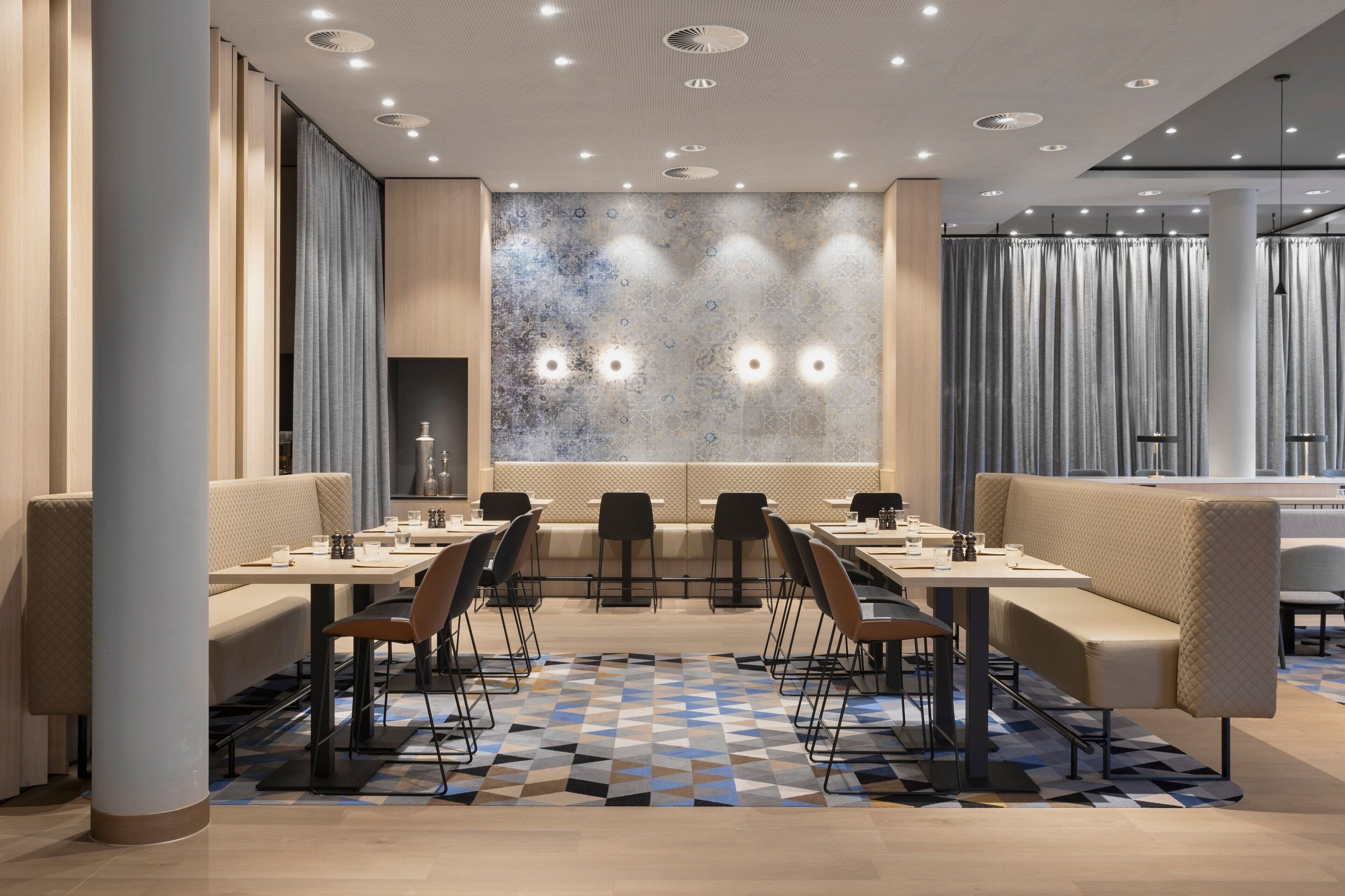 A modern dining area with a long table, multiple chairs, and cushioned seating.