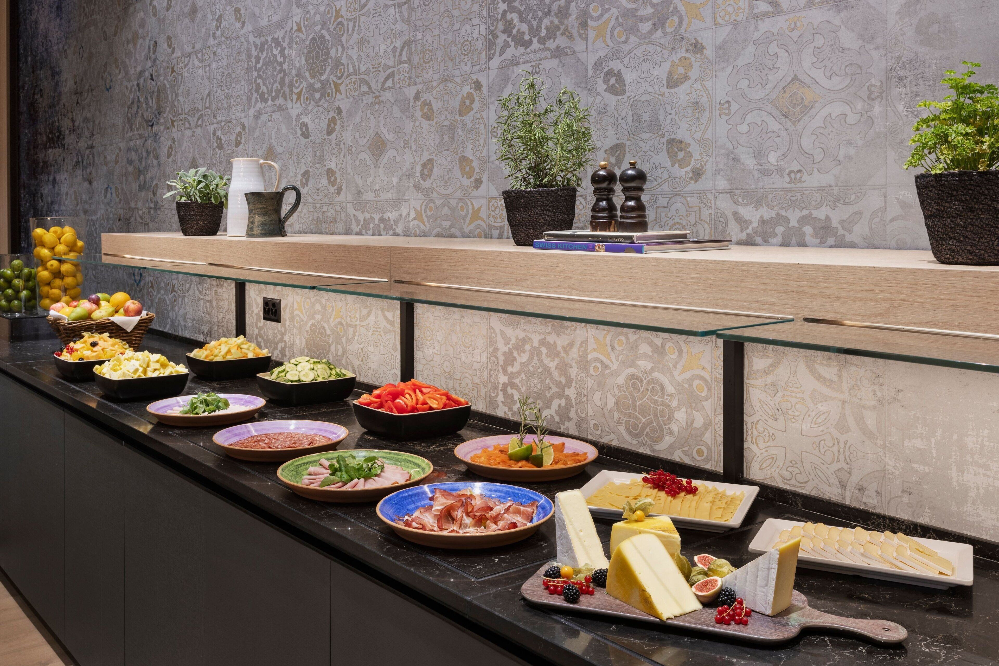 Un bufé con diferentes platos y una pared decorativa con baldosas estampadas.