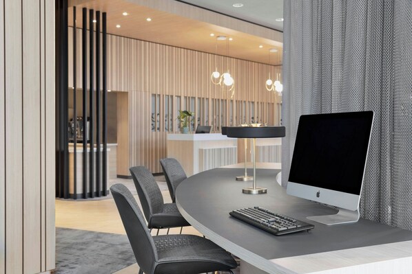 A modern conference room with a round table, black chairs, a large monitor, and a keyboard. - Courtyard by Marriott Basel (Pratteln)