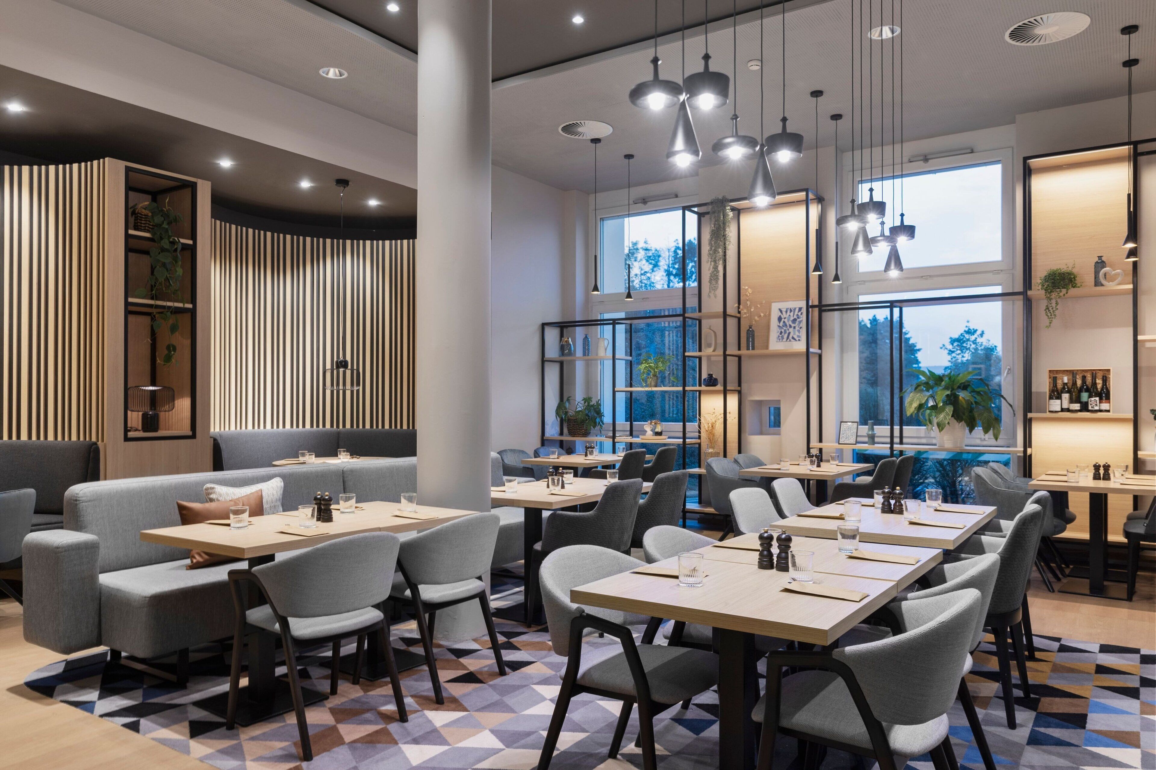 A modern restaurant with high tables and chairs, wooden paneling, and large windows.