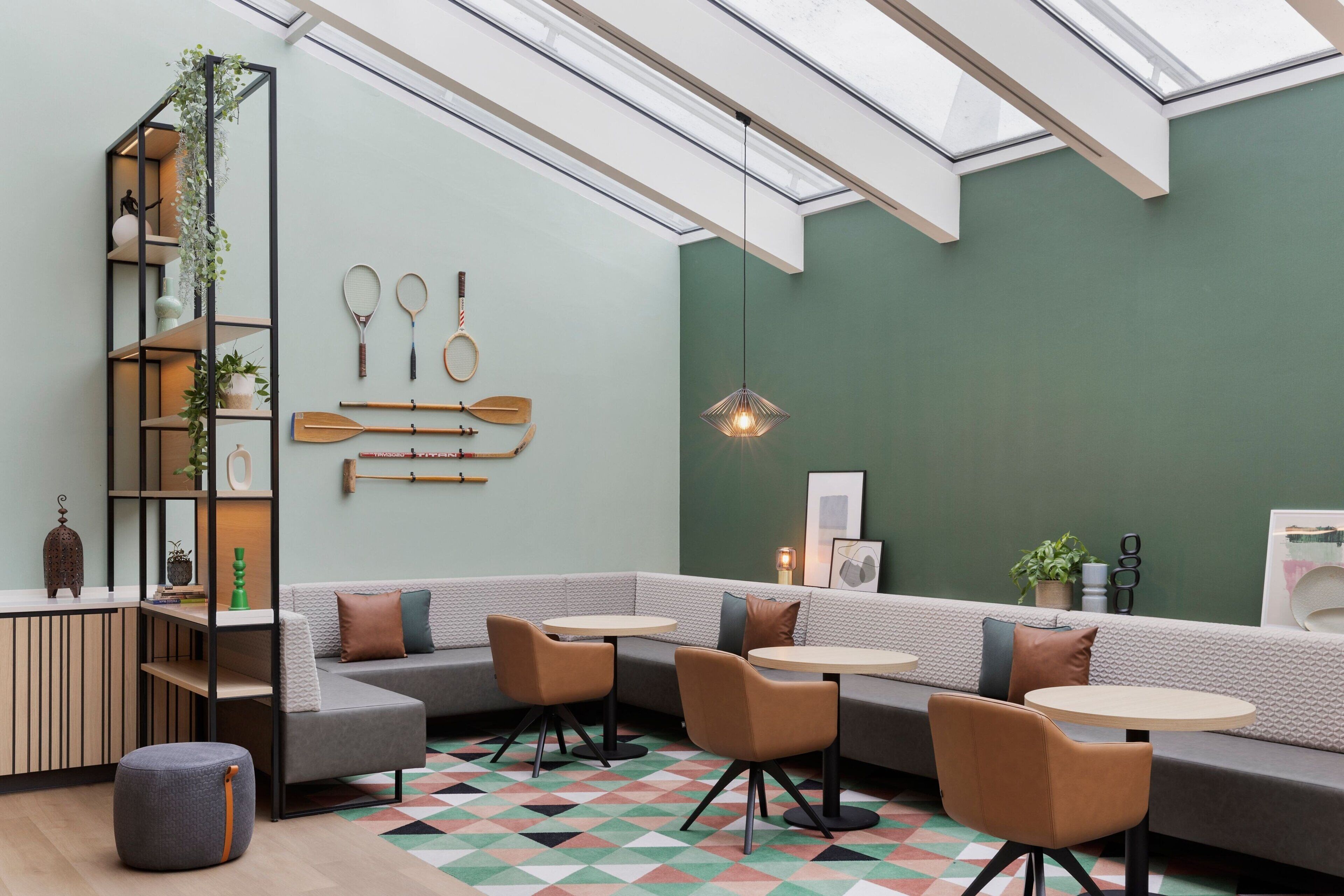 A modern interior with a sectional sofa, round tables, and a geometric patterned floor.
