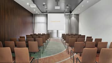 Un salón de conferencias con filas de sillas marrones, una pantalla grande que muestra 'COURTYARD' y un techo moderno con iluminación empotrada.