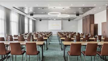 A conference room with rows of tables and chairs, a projector screen, and a "COURTYARD" sign.