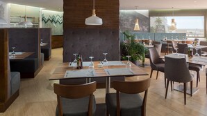 Ein modernes Restaurant mit Sitzgelegenheiten in Form von Boxen und Tischen und Blick ins Freie.