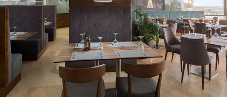 A modern restaurant with booths, tables, and a view of the outdoors.