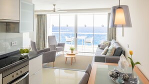 Ein modernes Hotelzimmer mit Küche, Essbereich und einem Balkon mit Meerblick.