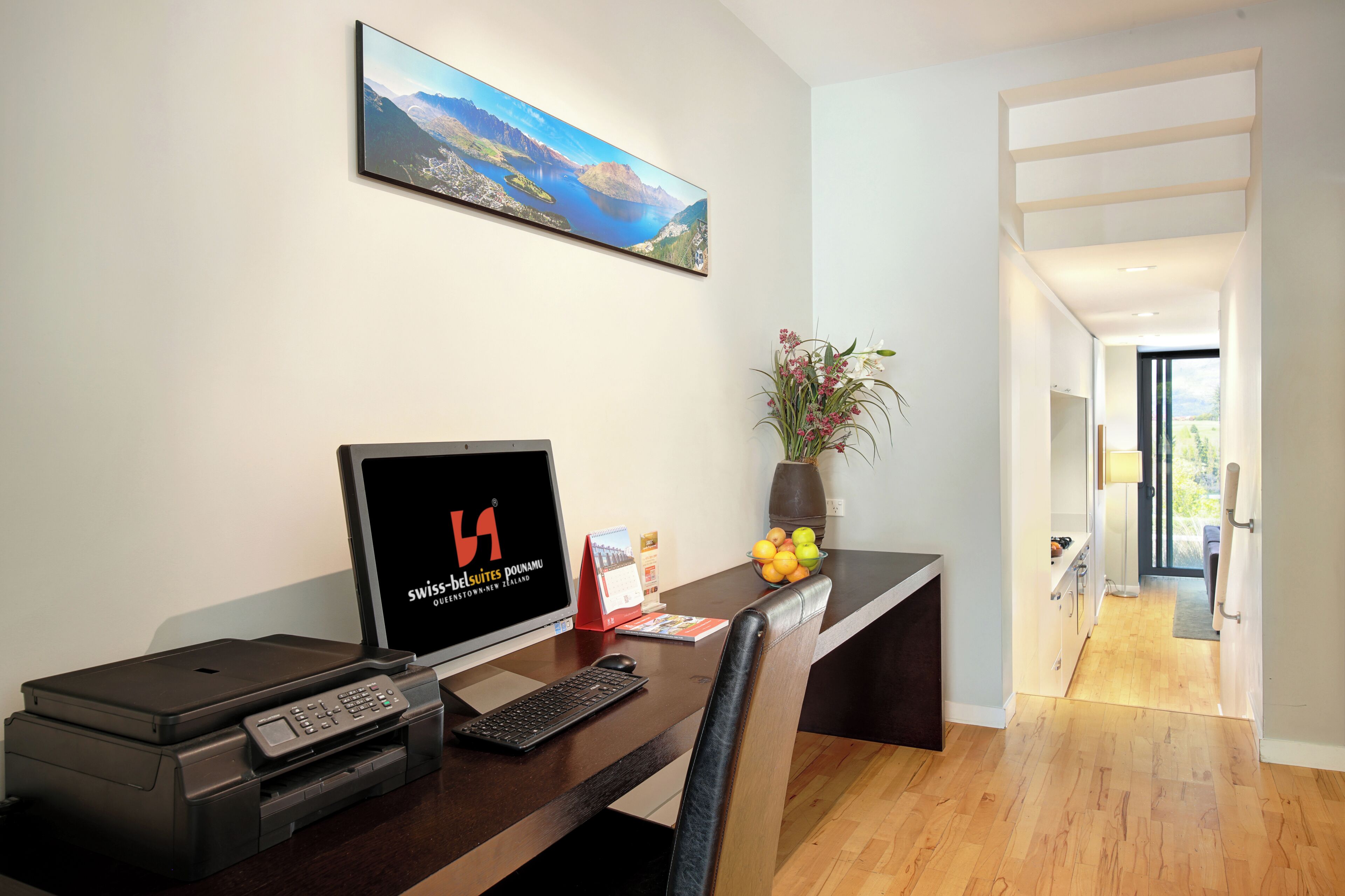 A modern hotel room with a desk, printer, and a large window offering a scenic view.