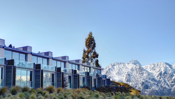 Un edificio moderno con amplios ventanales y montañas al fondo.