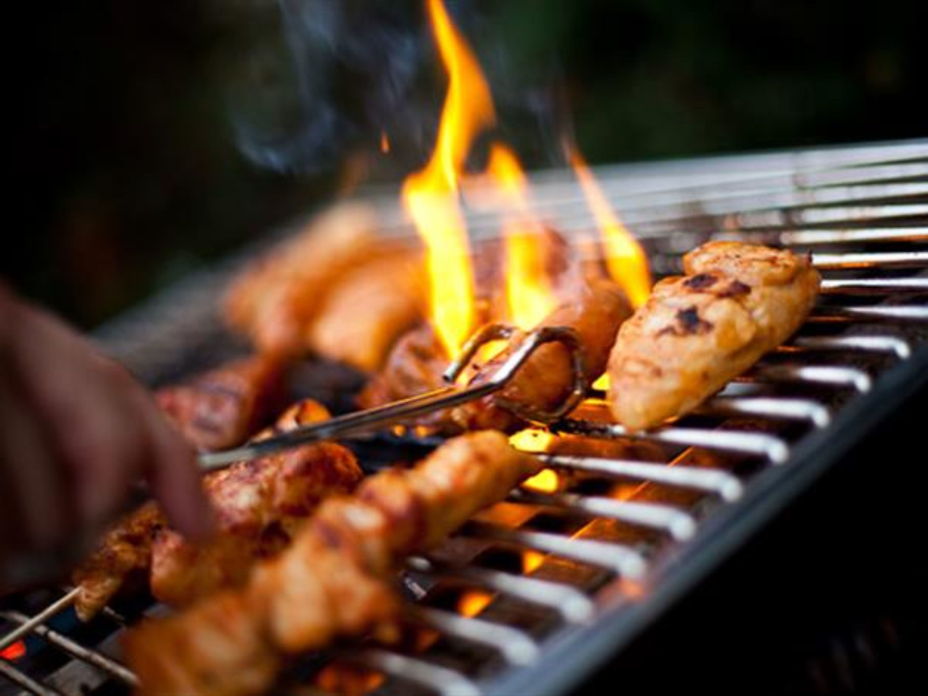 Una parrilla con brochetas de carne asándose sobre fuego abierto.