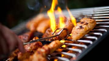 Una parrilla con brochetas de carne asándose sobre fuego abierto.