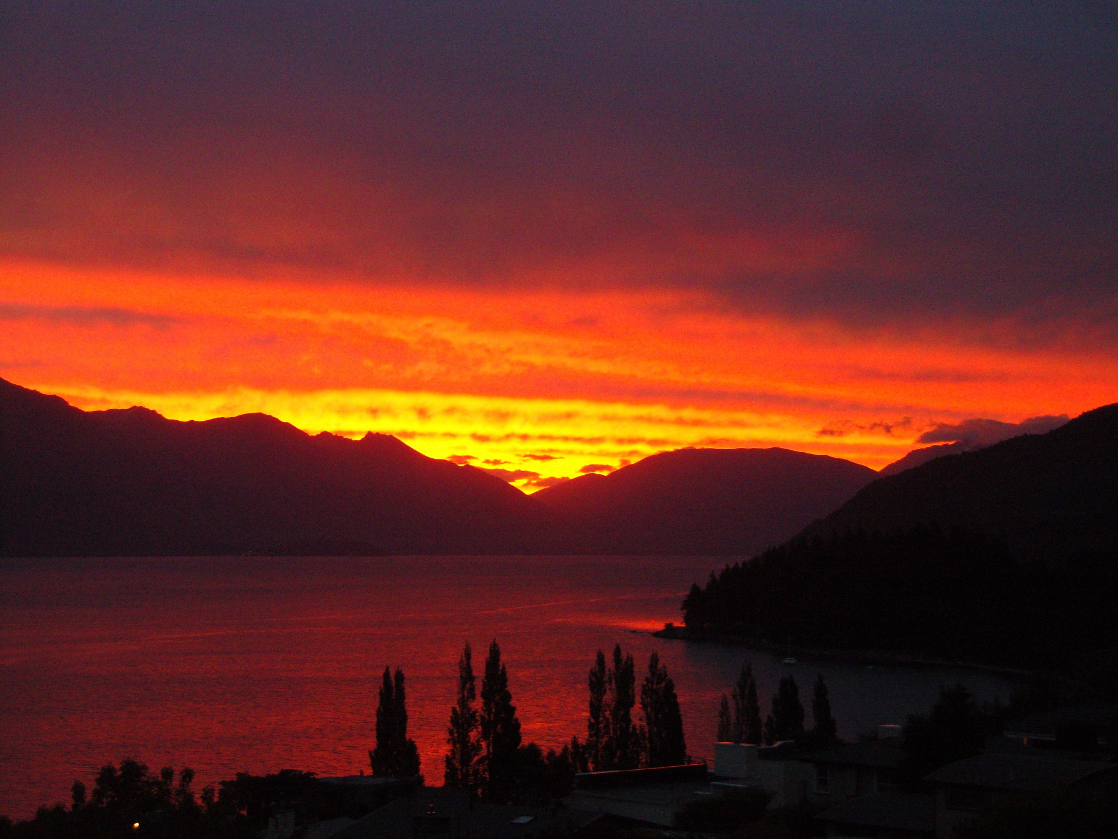 A sunset over a lake with mountains in the background.