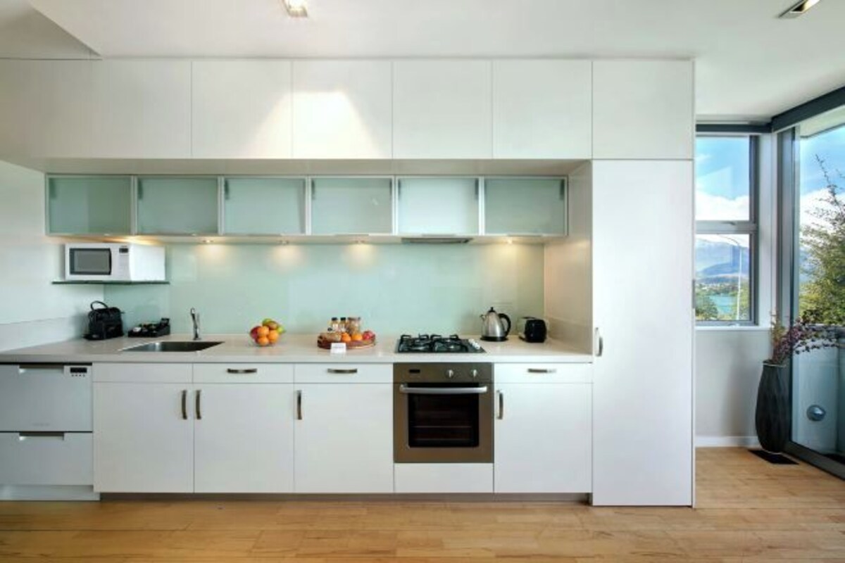 A modern kitchen with white cabinets, a microwave, a sink, and a stove.