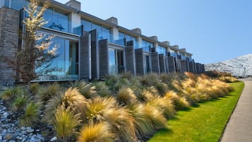 Stylish building with balconies and expansive windows, set amidst a beautifully manicured lawn.