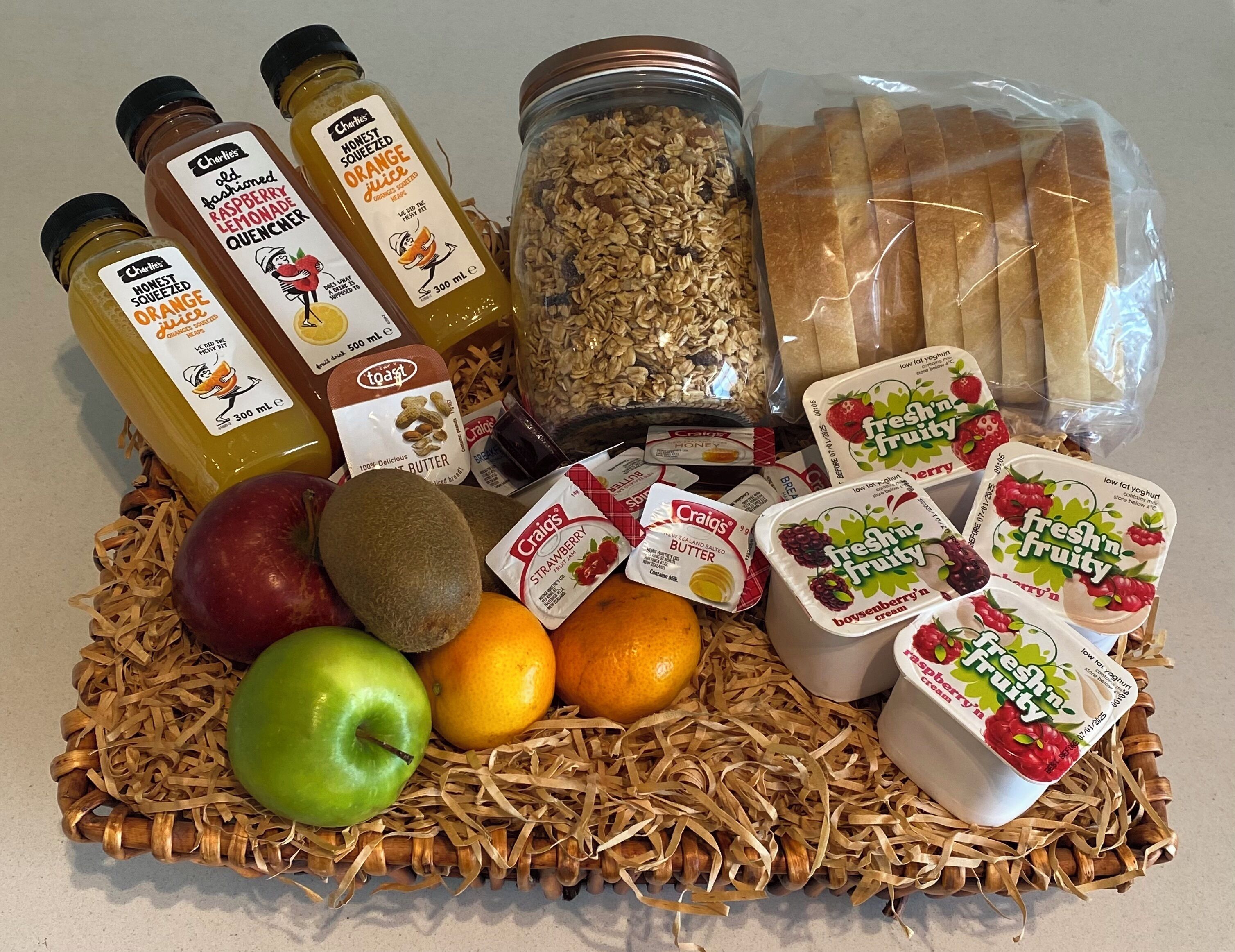 Une variété d’aliments, notamment des bouteilles de jus d’orange, des céréales, du pain et des yaourts, sont disposés sur une table.