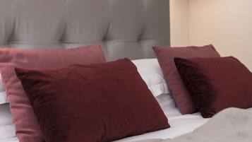 Uma cama com cabeceira estofada e várias almofadas.