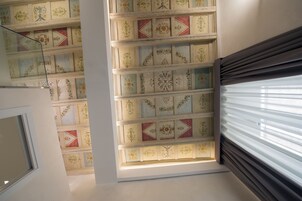 A room with a skylight, a window with blinds, and a decorative ceiling with patterned tiles.