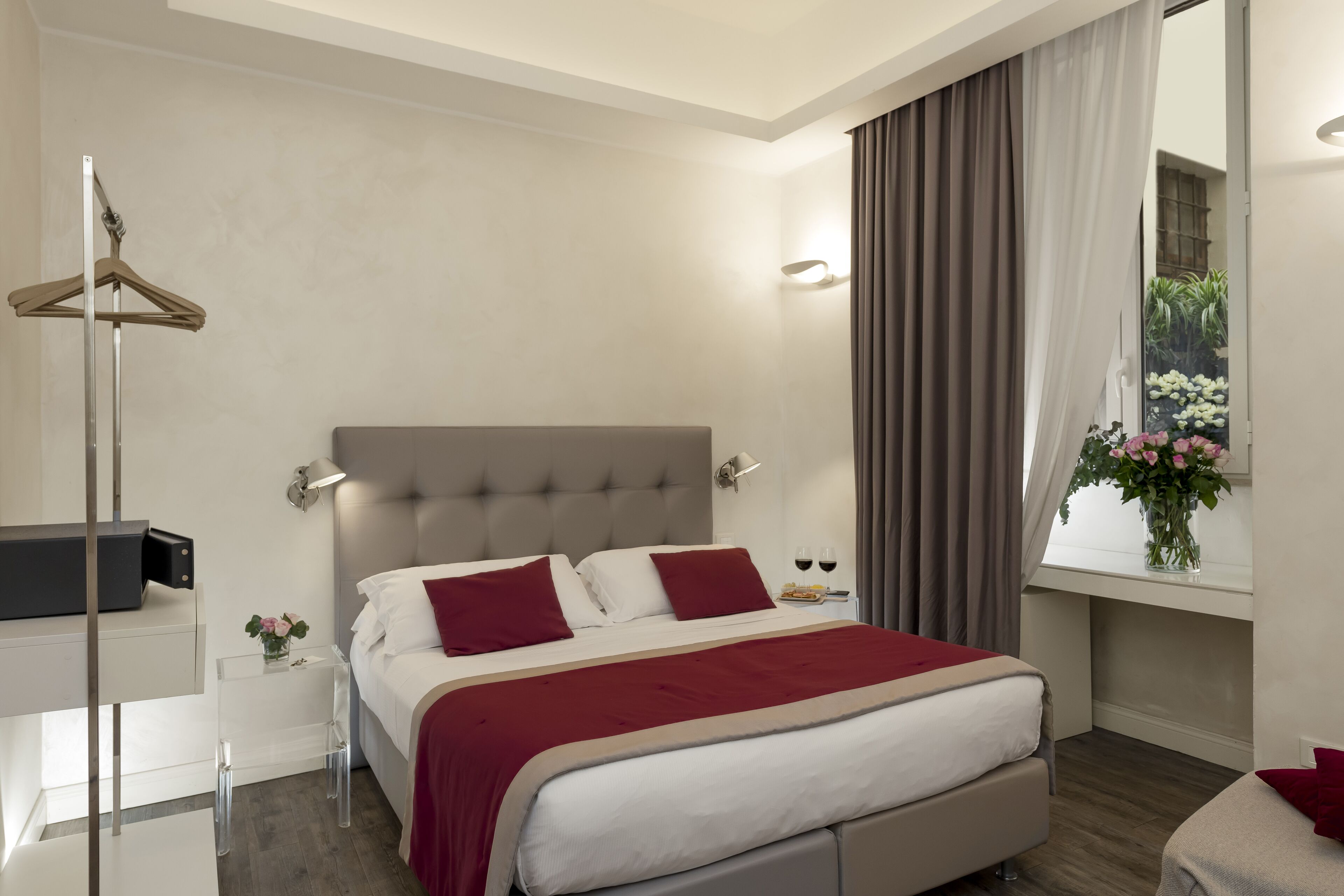 A modern bedroom with a large bed, bedside tables, a wardrobe, and a window with curtains.