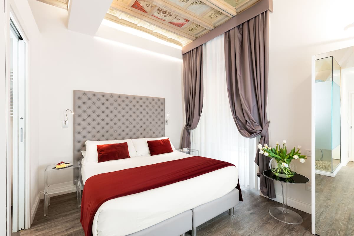 A modern hotel room with a large bed, a glass table, and a mirror.