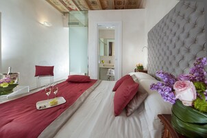 A hotel room with a bed, a bedside table, a mirror, and a view of the bathroom.