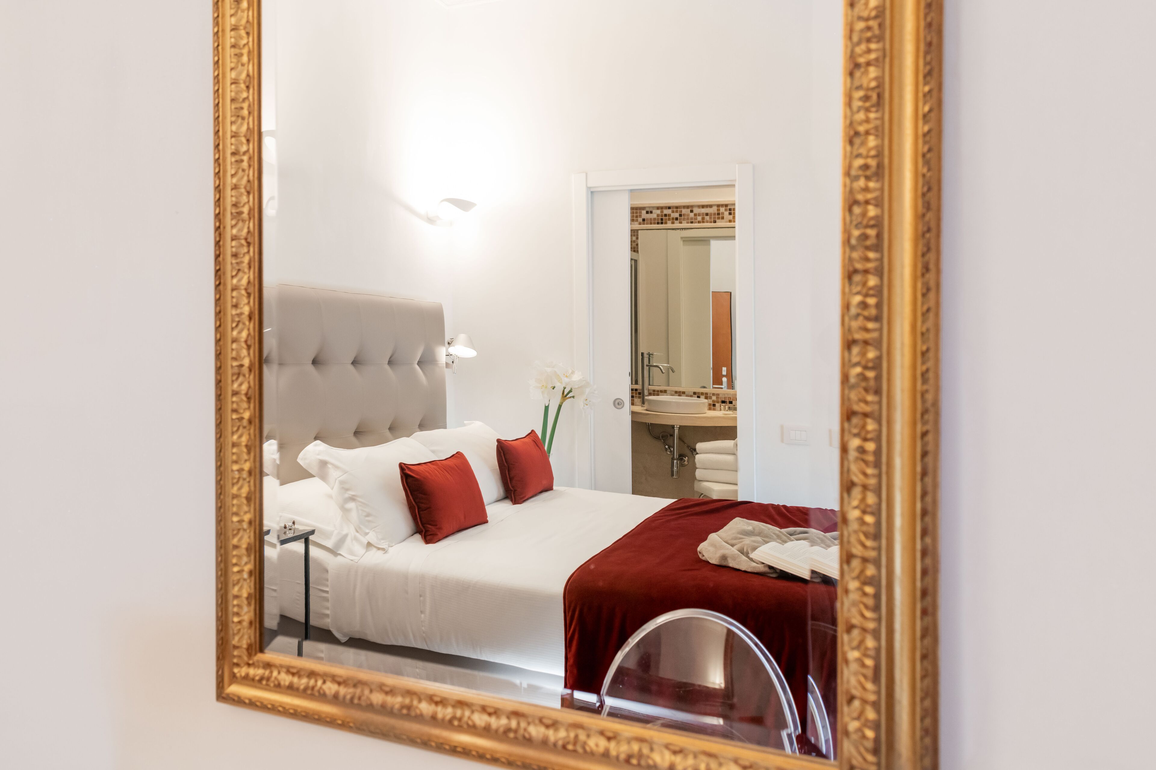 A hotel room with a large bed, a mirror, and a bathroom visible through an open door.