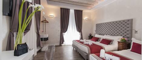 A hotel room with two beds, a desk, and a chair. There are curtains, a TV, and a ceiling with exposed beams.