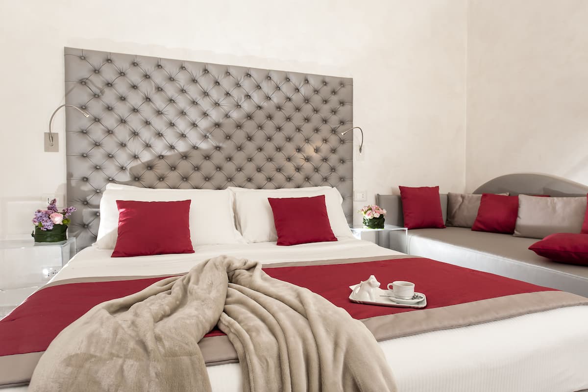 A hotel room with a large bed, a sofa bed, and a separate armchair.