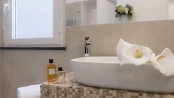 Un baño moderno con un lavamanos ovalado grande, una toalla y dos botellas de jabón líquido.