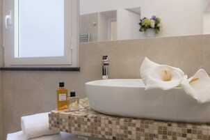 A modern bathroom with a large oval sink, a towel, and two bottles of liquid soap.