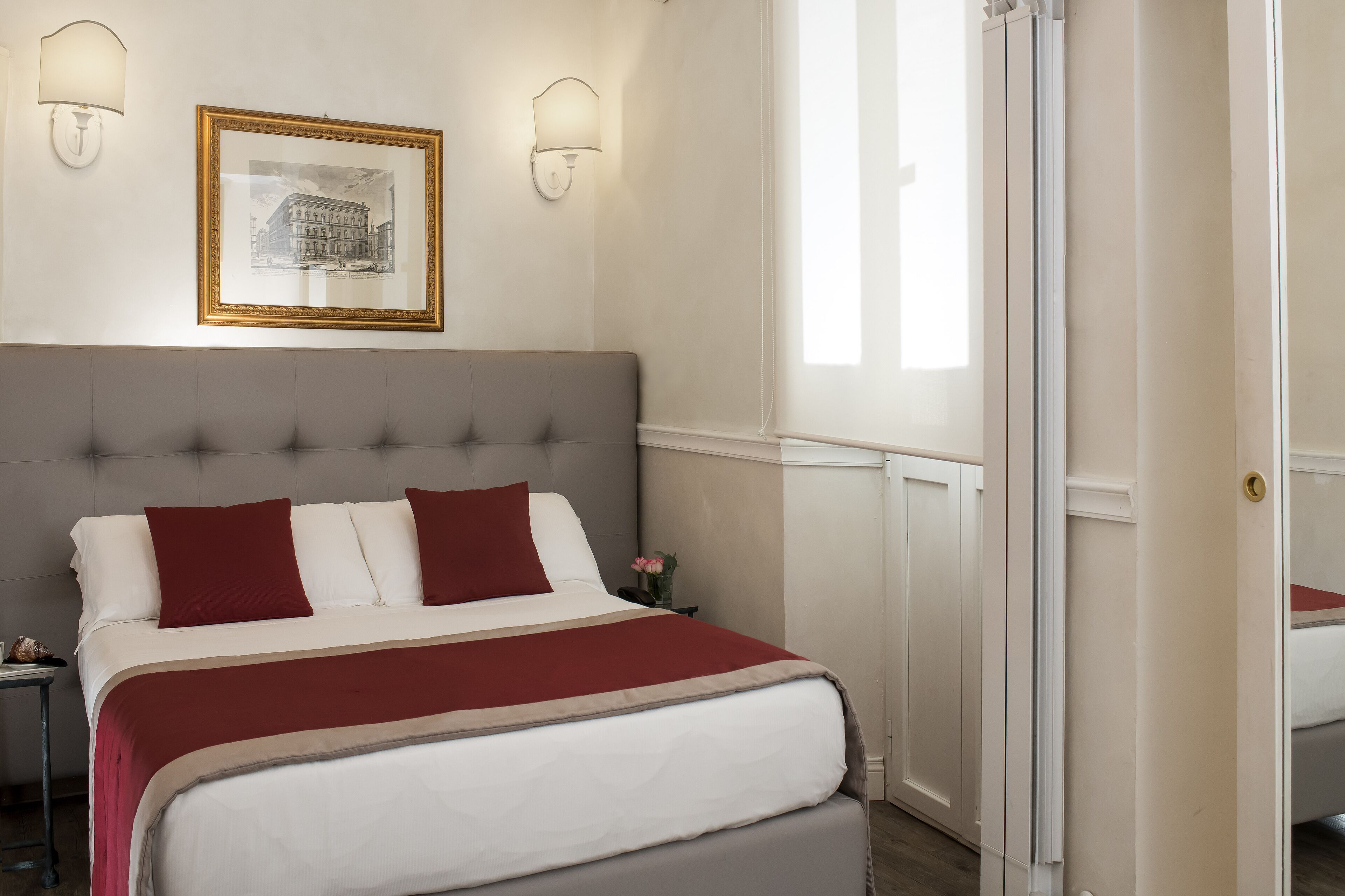 Quarto bem arrumado com uma cama grande, um quadro na parede e duas luminárias.