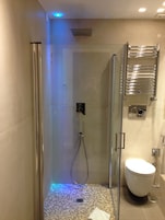 Un bagno moderno con doccia vetrata, un water e un porta asciugamani.