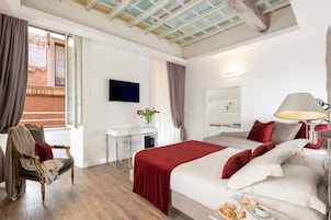 A hotel room with a large bed, a desk, a chair, a television, and a window with curtains.