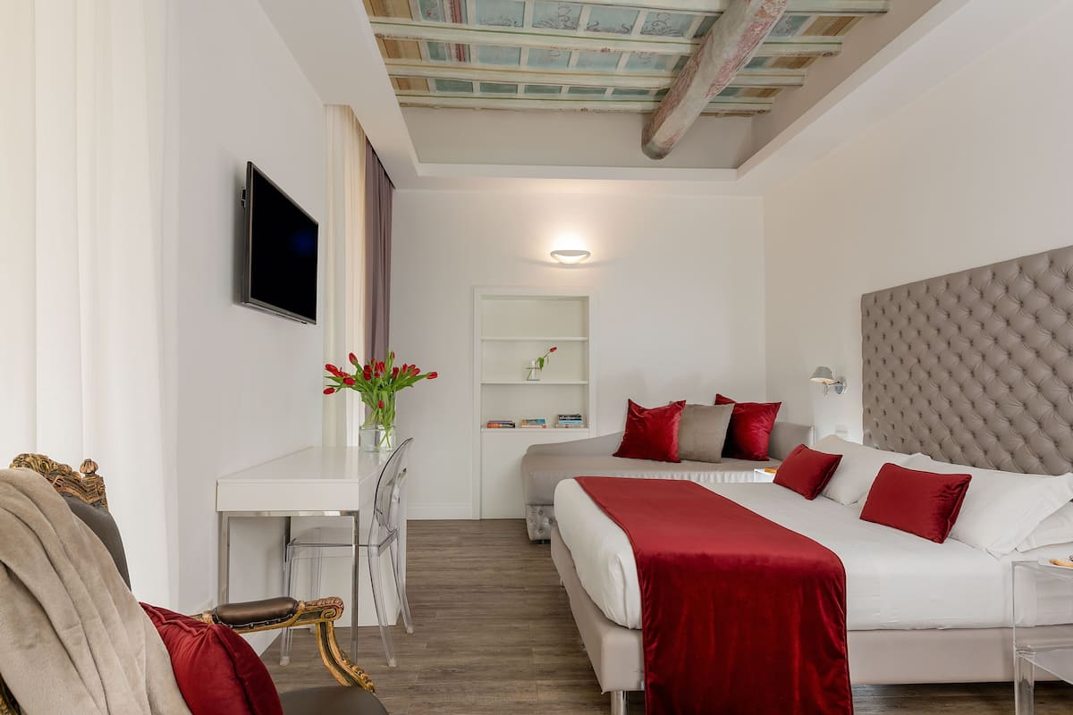 A modern hotel room with a large bed, a desk, and a television.