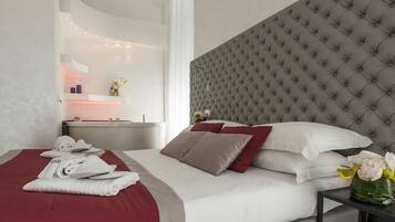 A modern hotel room with a large bed, a grey tufted headboard, and a bedside table with a vase of flowers.