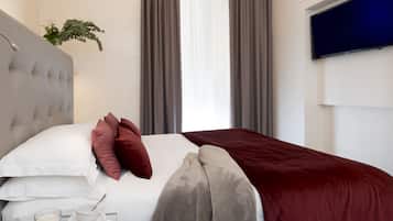 A neatly made bed with white and maroon pillows, a grey headboard, and a red blanket.