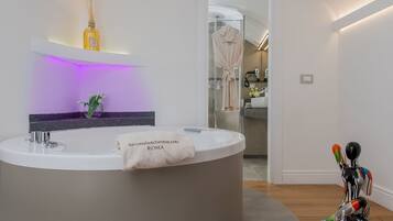 A modern bathroom with a round sink, a towel rack, a bottle of reed diffuser, and a robe hanging on a door.